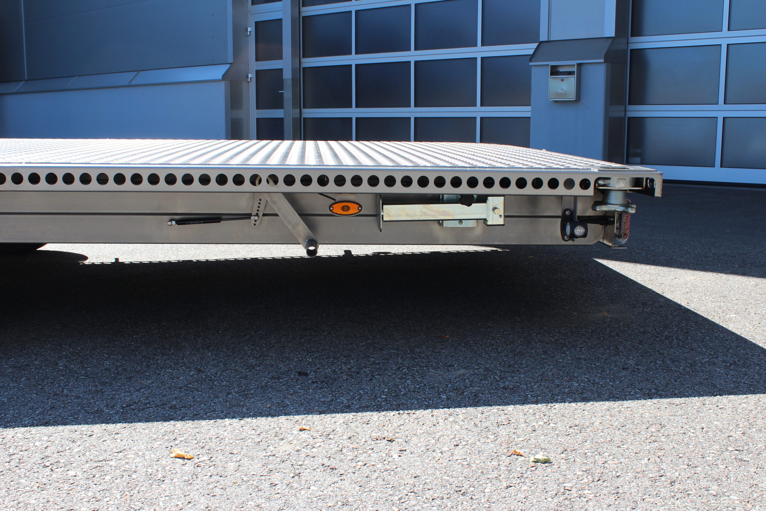 UA600 Container8 Edelstahl Plattform Anhänger mit Twistlock aufnahmen an den 4 Ecken zum Befestigen eines Übersee-Containers. Containertransporter und Plattformanhänger vor einer Halle
