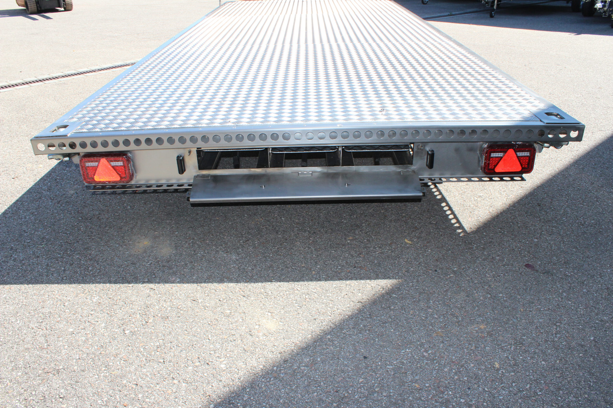 UA600 Container9 Edelstahl Plattform Anhänger mit Twistlock aufnahmen an den 4 Ecken zum Befestigen eines Übersee-Containers. Containertransporter und Plattformanhänger vor einer Halle