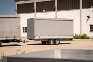 Grauer Planenanhänger vor einem Industriegebäude