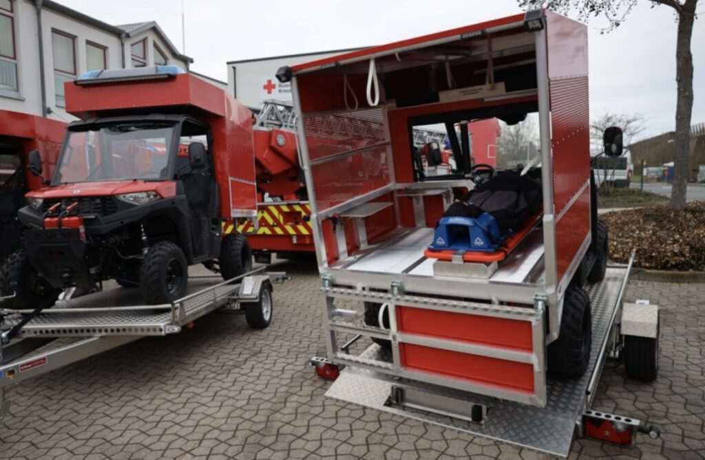 Aluminium Absenkanhänger mit umgebauten Rettungs-UTV in rot auf einem Hof