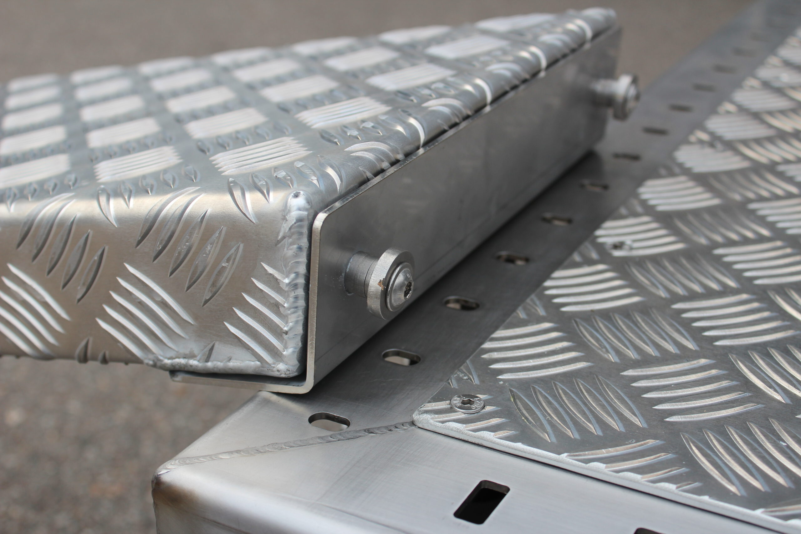 Aluminium Auffahrrampe mit Pins zum Befestigen an der Plattform in Edelstahl -- liegt auf einem Anhänger