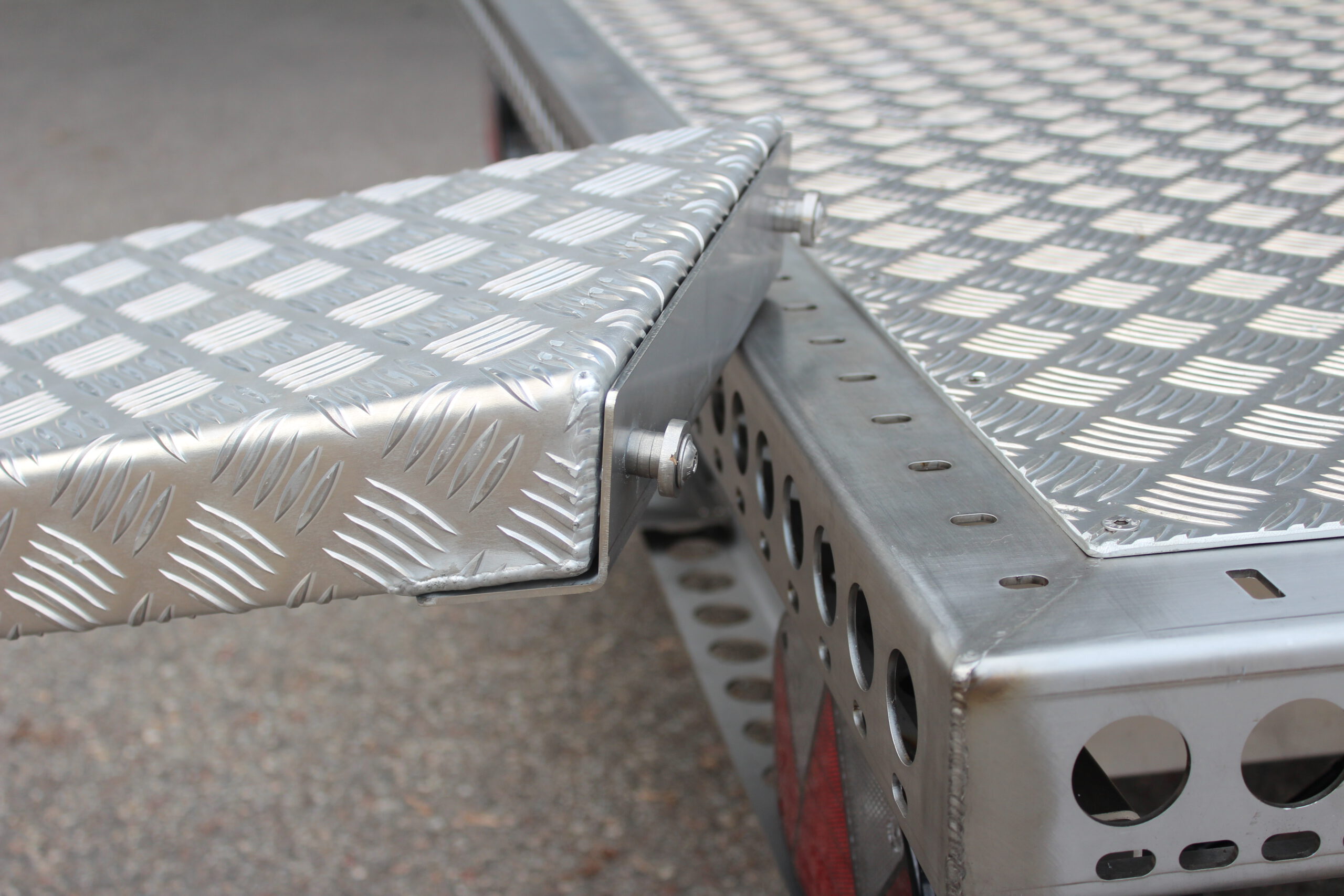 Aluminium Auffahrrampe mit Pins zum Befestigen an der Plattform in Edelstahl -- liegt auf einem Anhänger