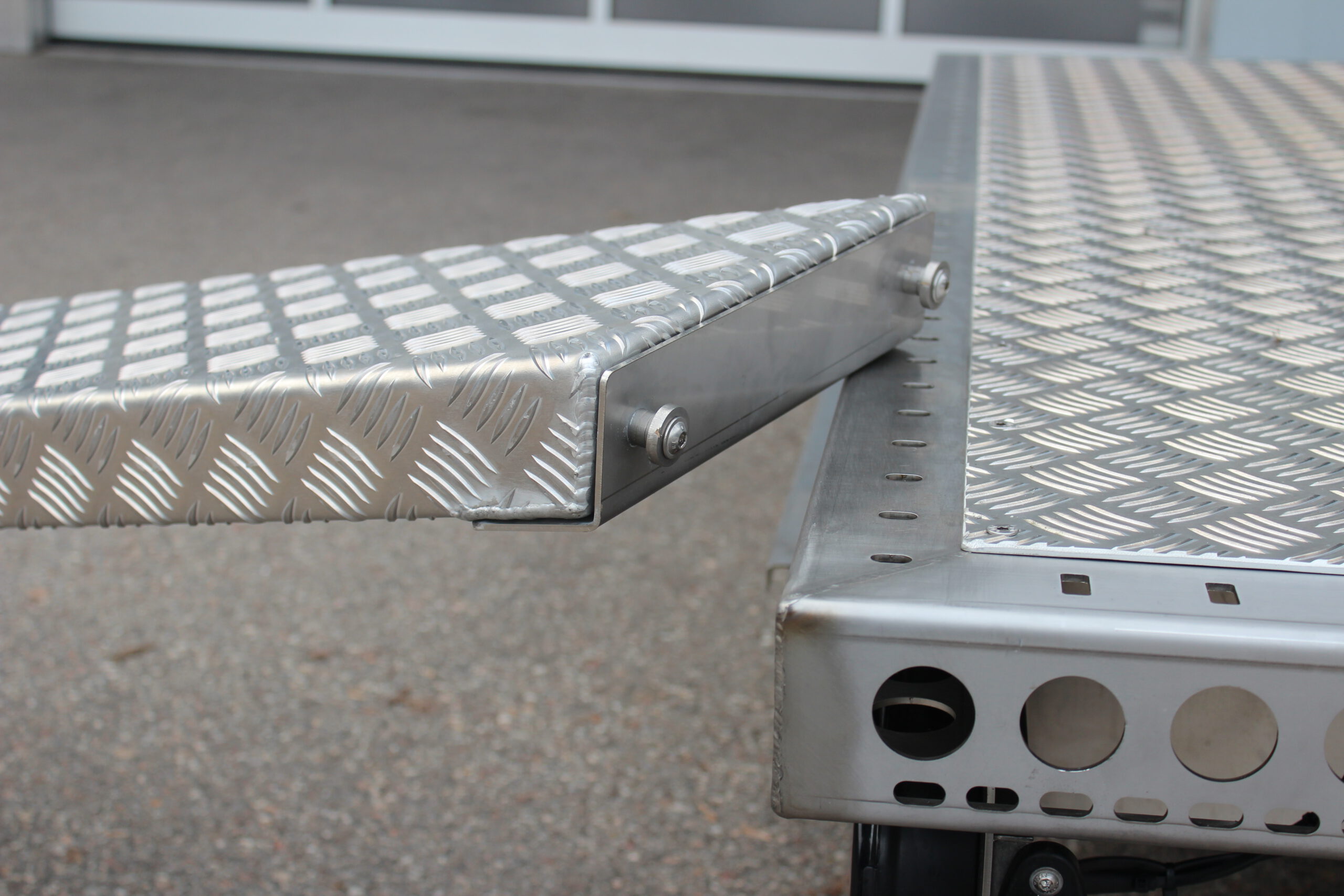 Aluminium Auffahrrampe mit Pins zum Befestigen an der Plattform in Edelstahl -- liegt auf einem Anhänger