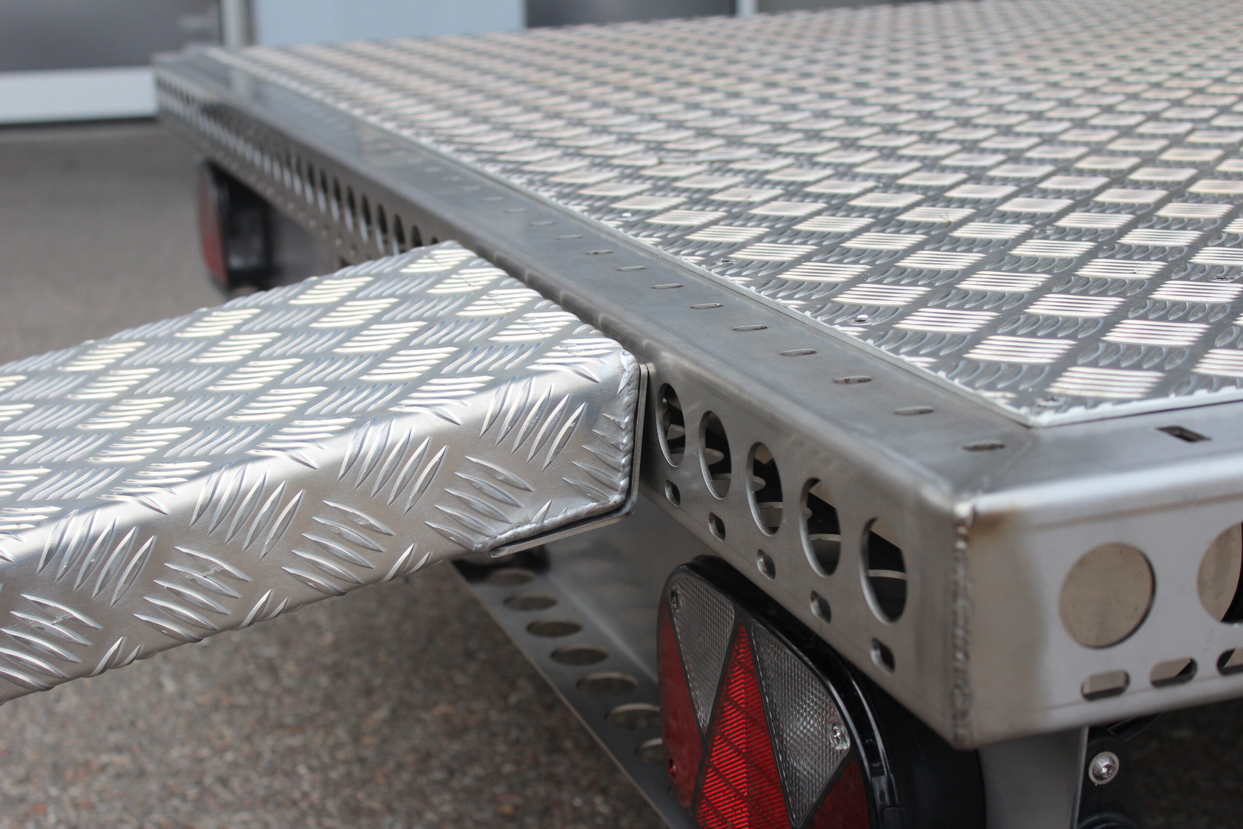 Aluminium Auffahrrampe mit Pins zum Befestigen an der Plattform in Edelstahl -- liegt auf einem Anhänger