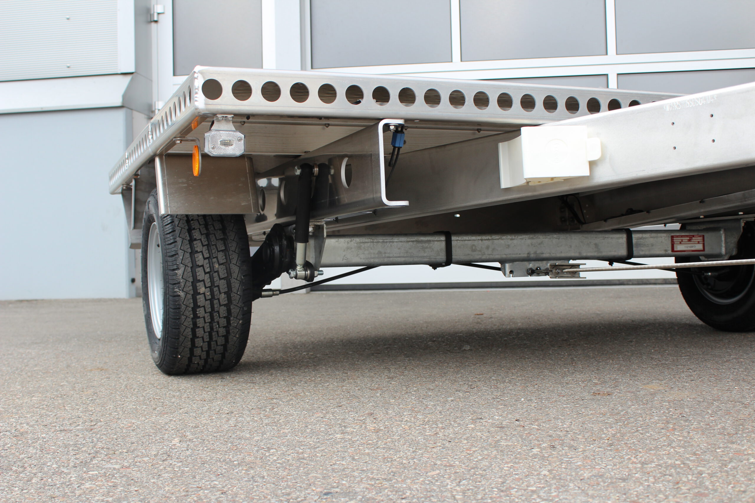 Kleiner Aluminium Plattformanhänger in silber vor einem grauen Hallentor