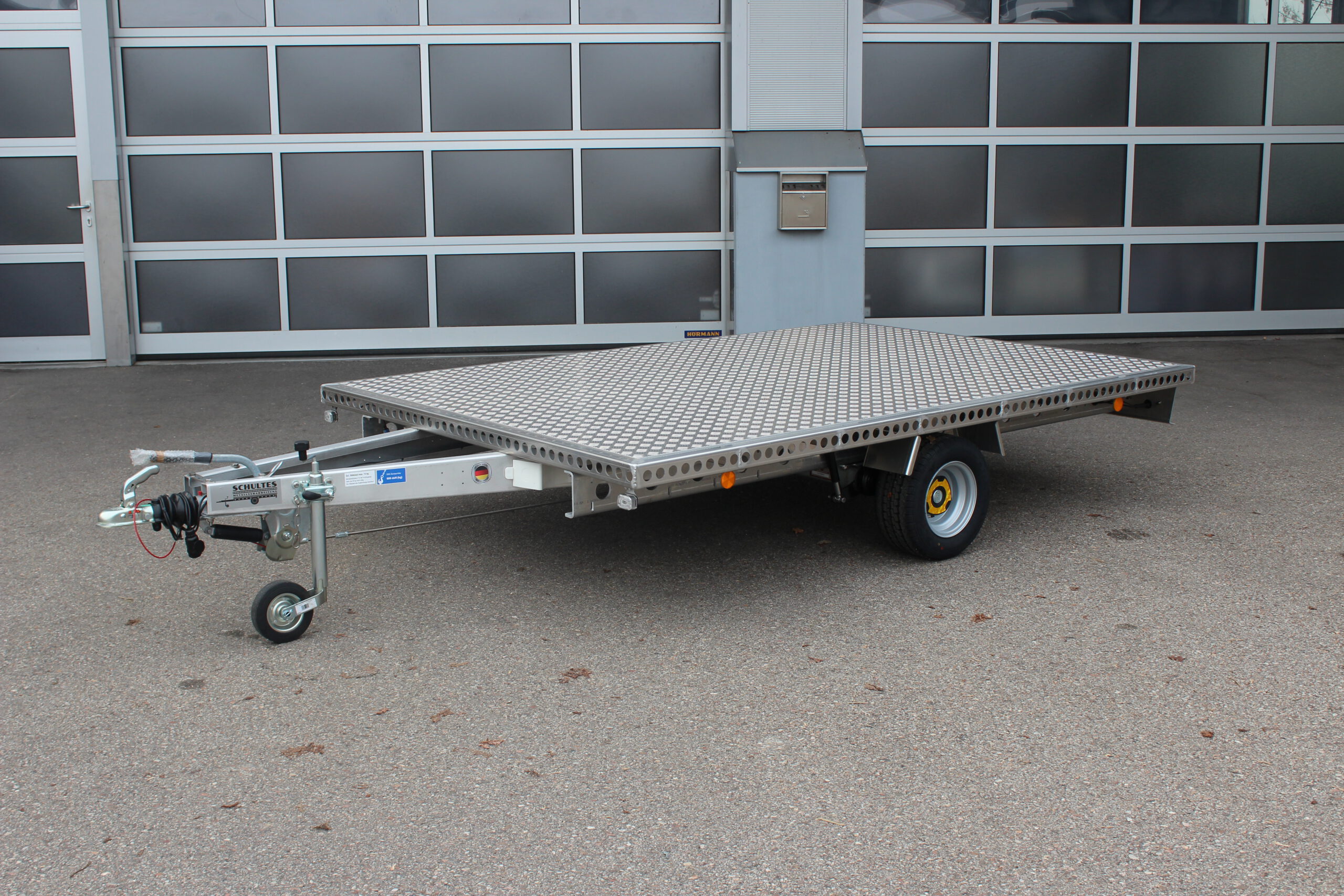 Aluminium Plattform-Anhänger 3,0m x 2,0m vor einem Hallentor