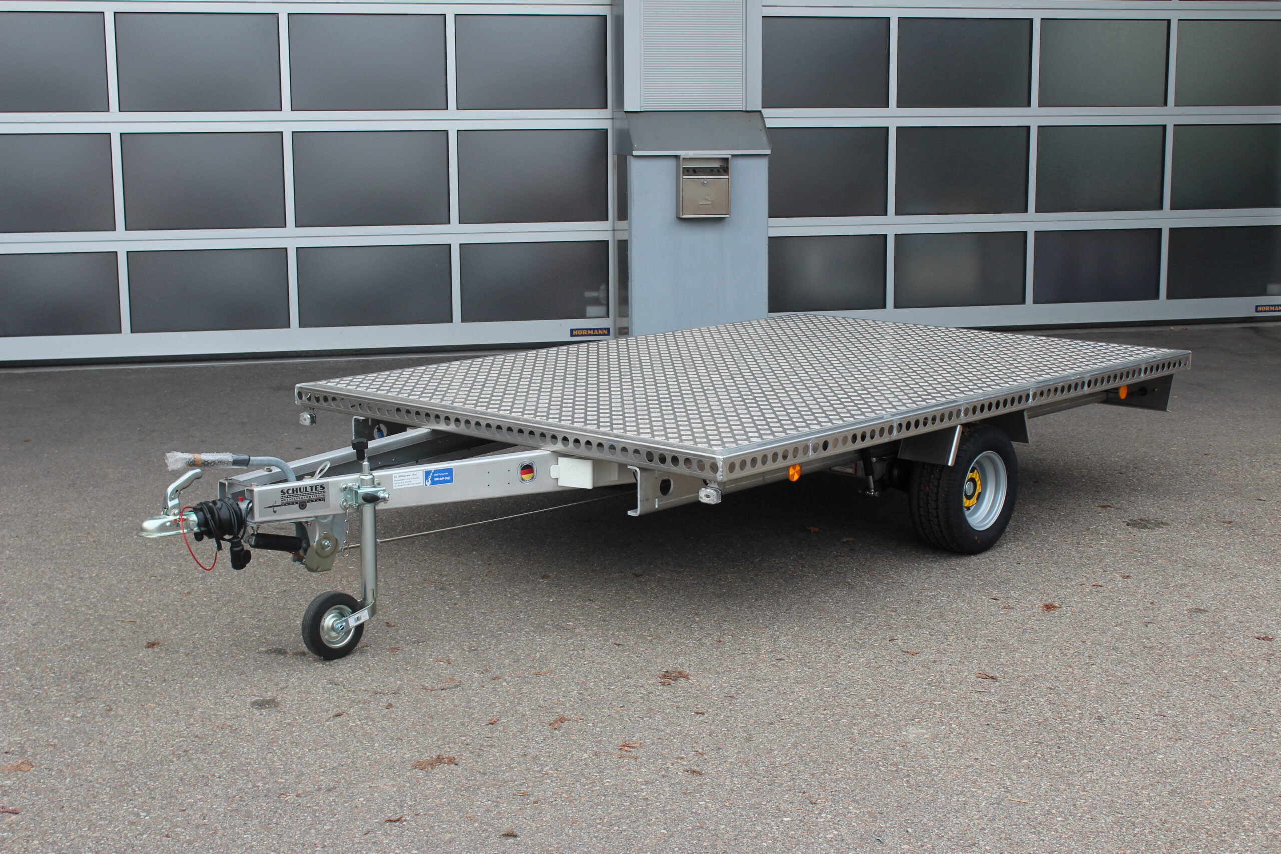 Aluminium Plattform-Anhänger 3,0m x 2,0m vor einem Hallentor