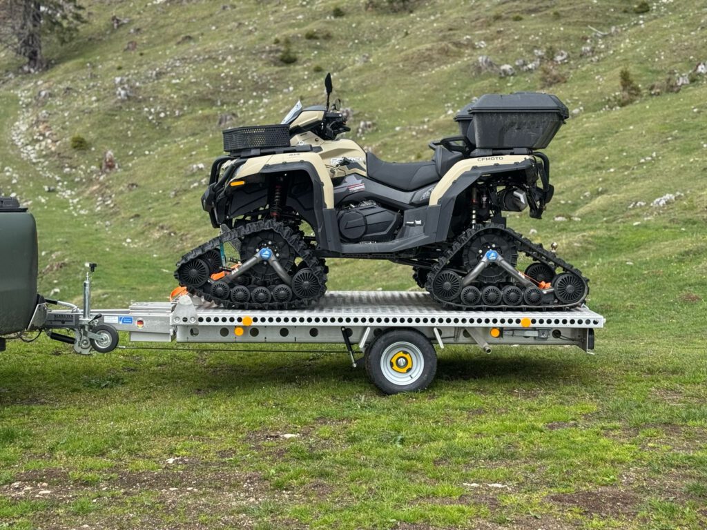 Aluminium Plattformanhänger mit einem grauen Quad beladen auf einer grünen Wiese