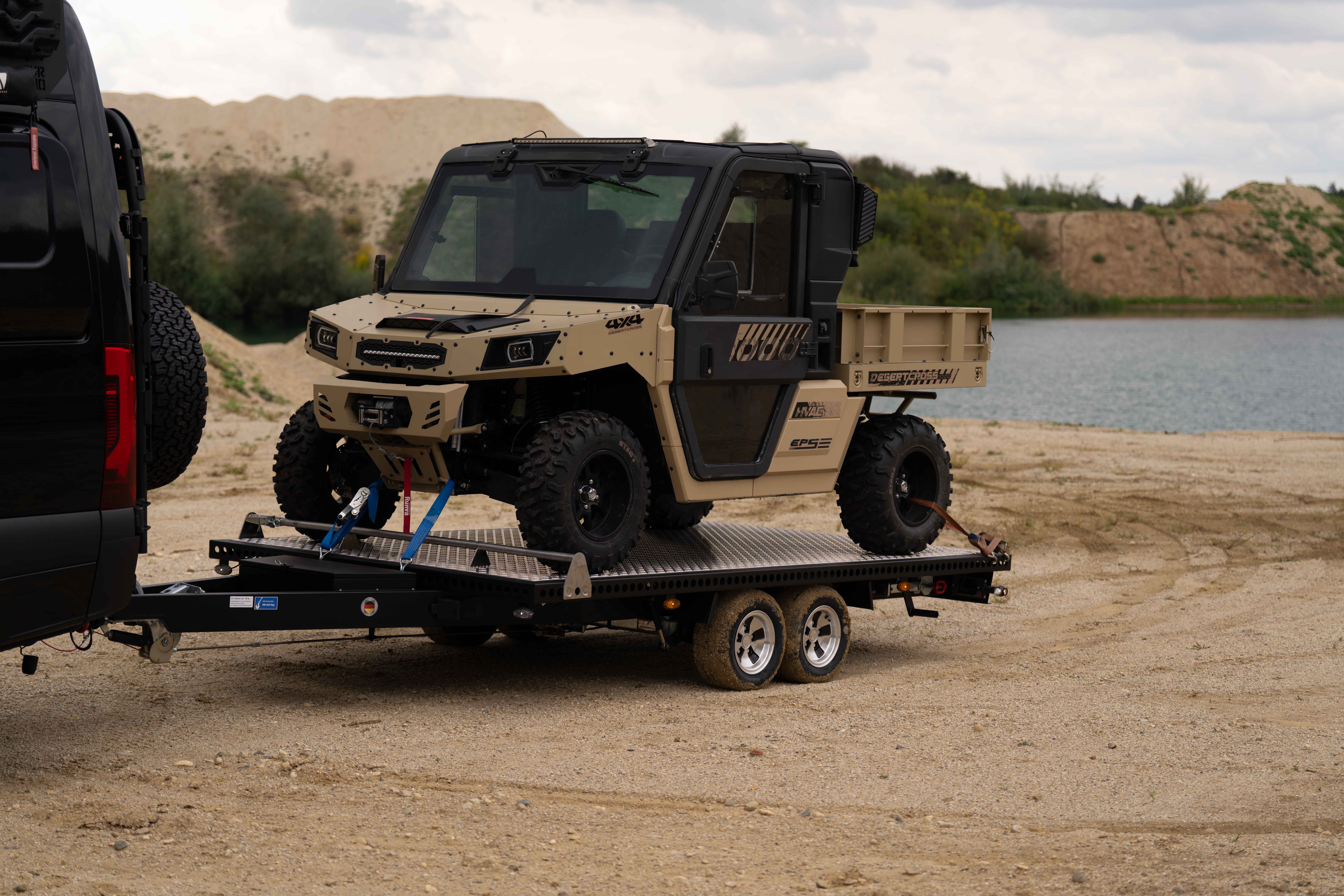 Schwarzer Edelstahl Autotransporter beladen mit einem UTV in einer Kiesgrube vor einem See