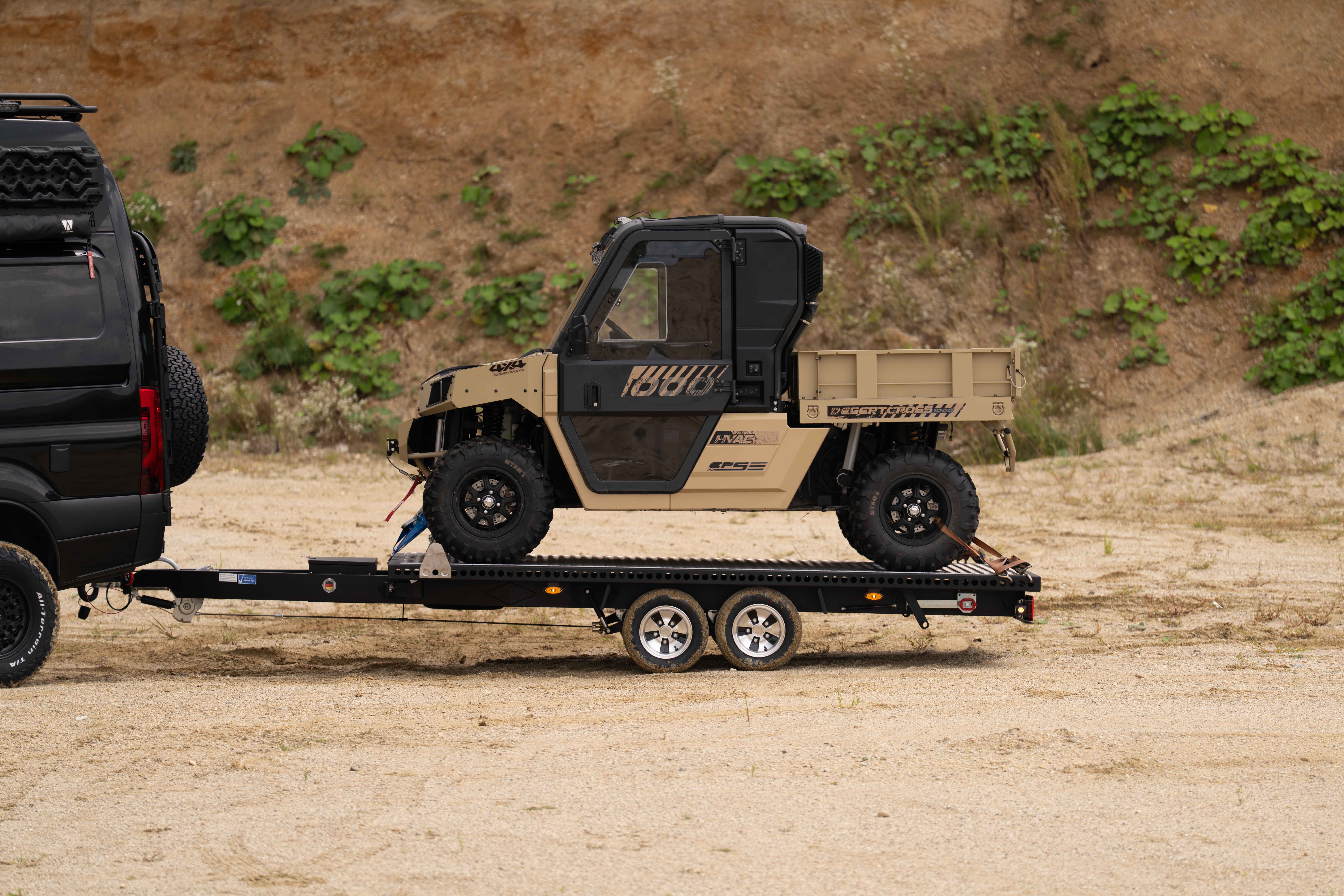 Schwarzer Edelstahl Autotransporter beladen mit einem UTV in einer Kiesgrube vor einem See