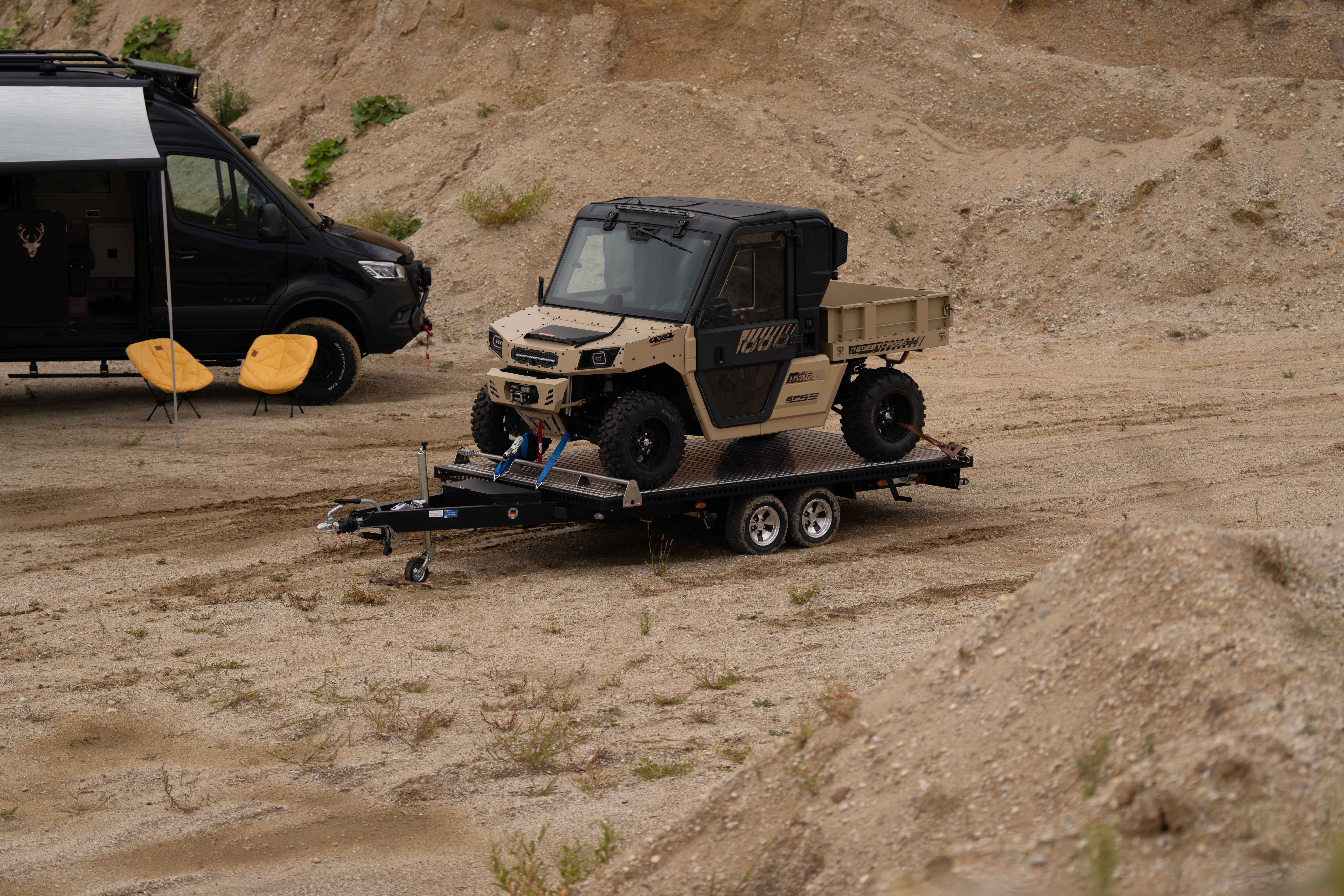 Schwarzer Edelstahl Autotransporter beladen mit einem UTV in einer Kiesgrube vor einem See