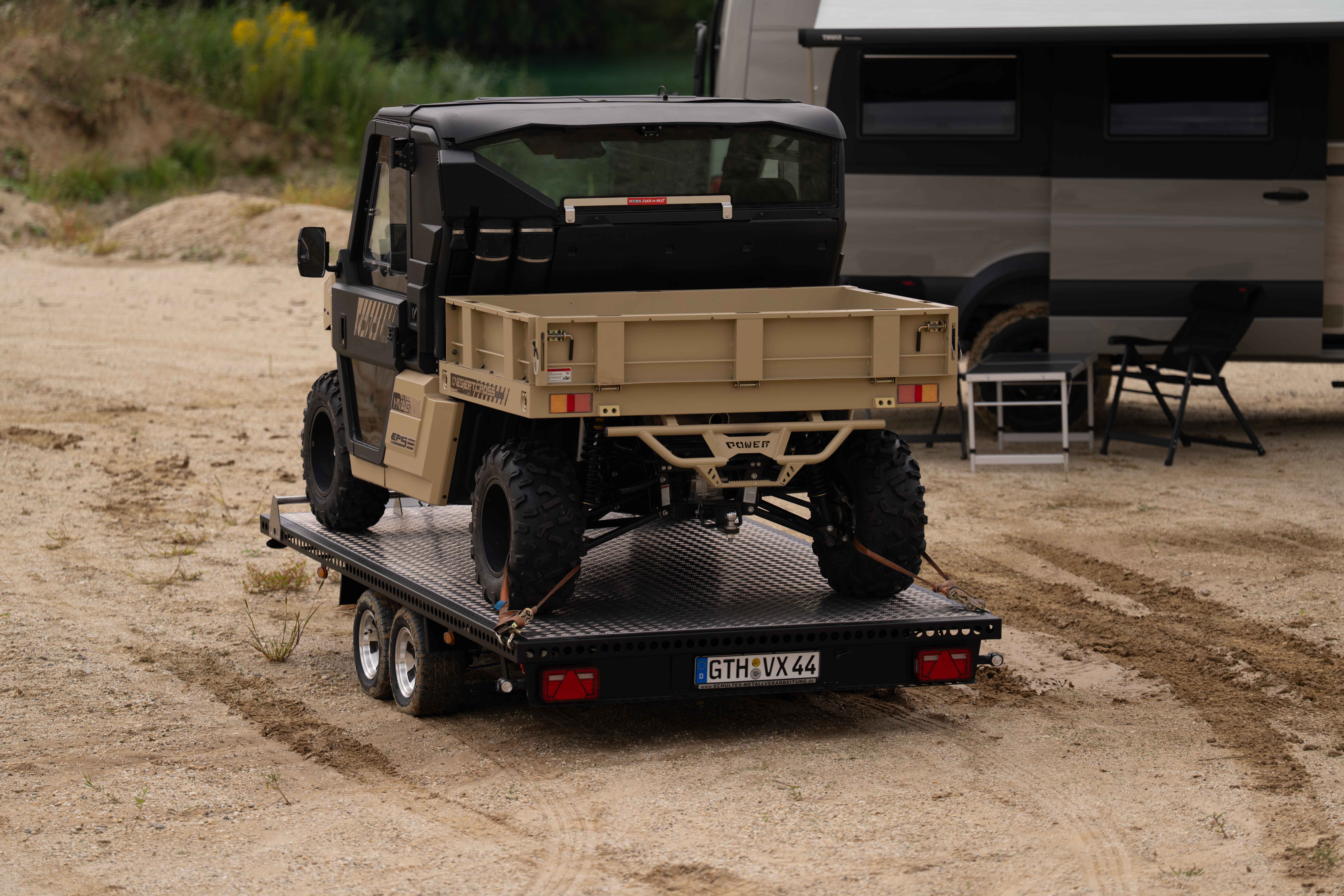 Schwarzer Edelstahl Autotransporter beladen mit einem UTV in einer Kiesgrube vor einem See