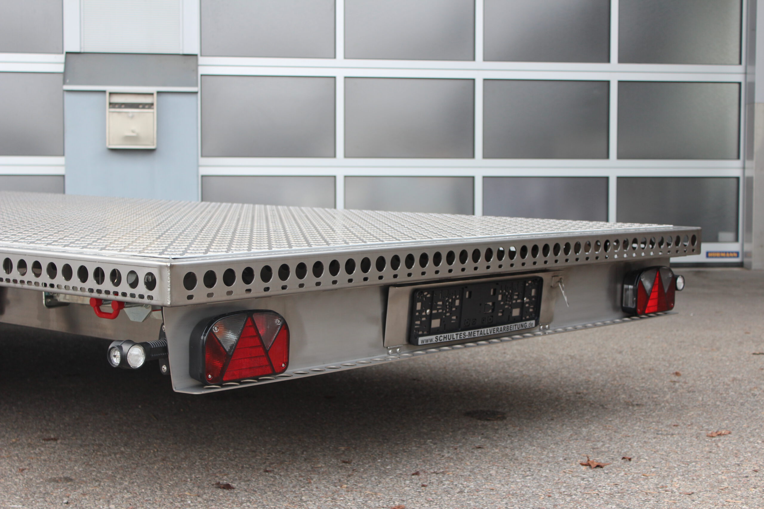 Zweiachs- Edelstahl Plattform-Anhänger, silber, vor einem Hallentor