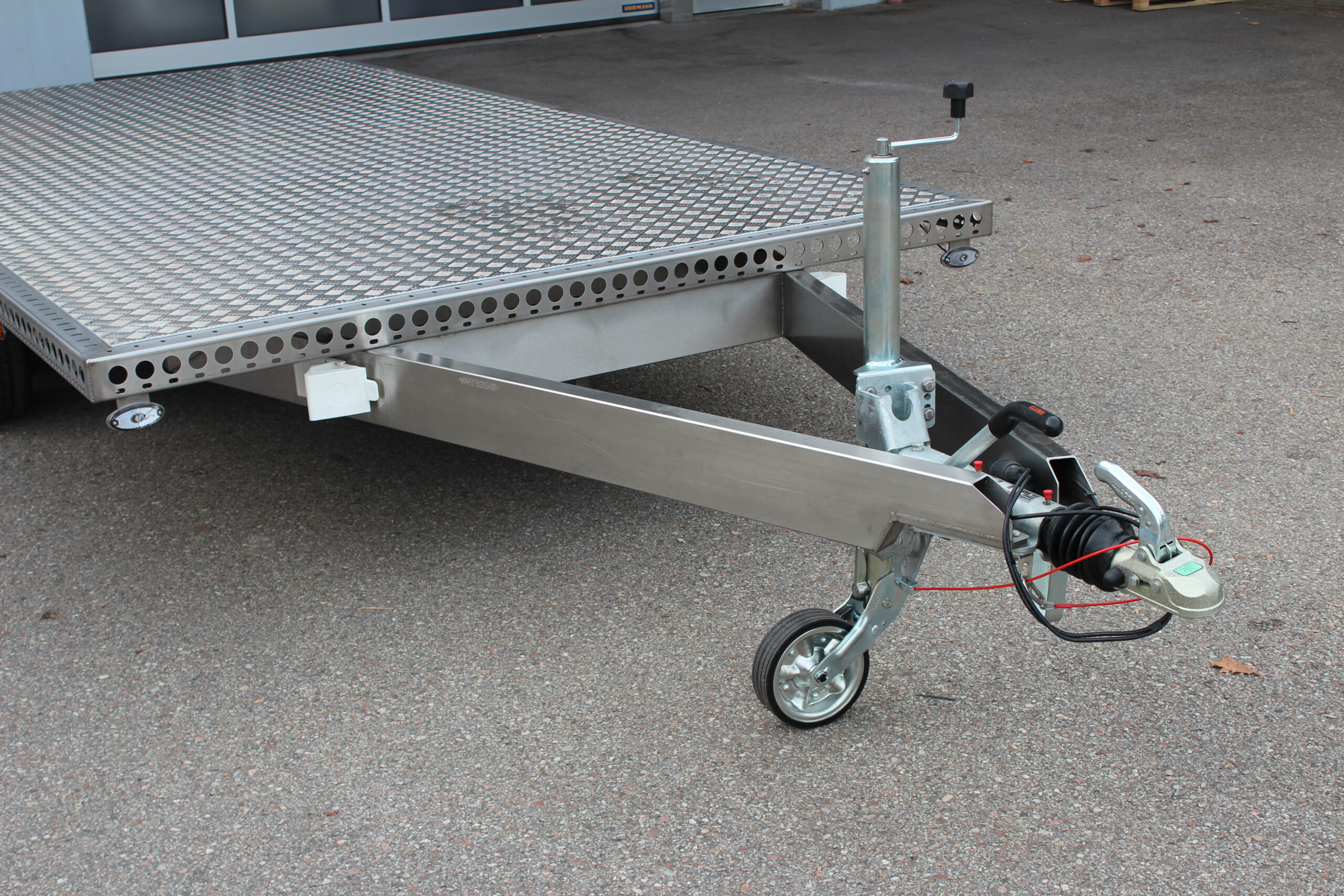 Zweiachs- Edelstahl Plattform-Anhänger, silber, vor einem Hallentor