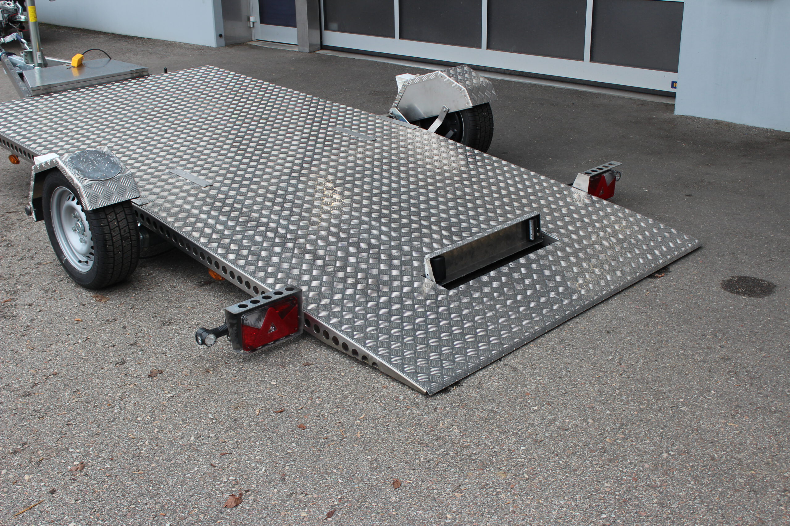 Absenkbarer Anhänger aus Edelstahl vor einem Hallentor