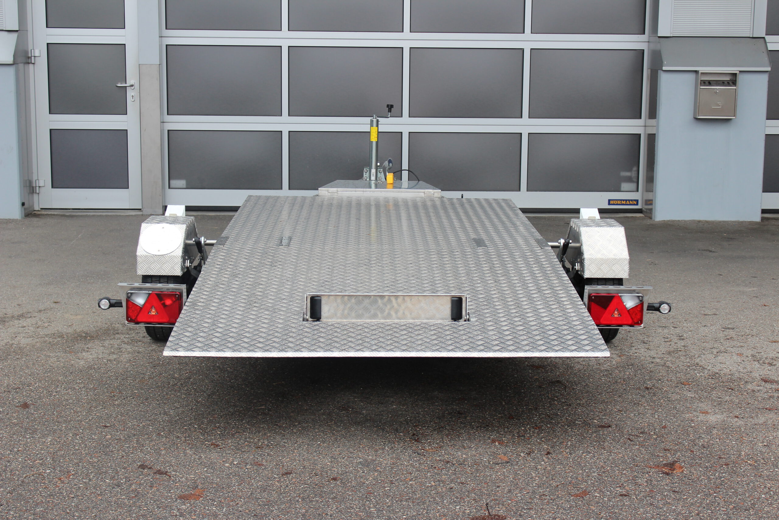 Absenkbarer Anhänger aus Edelstahl vor einem Hallentor