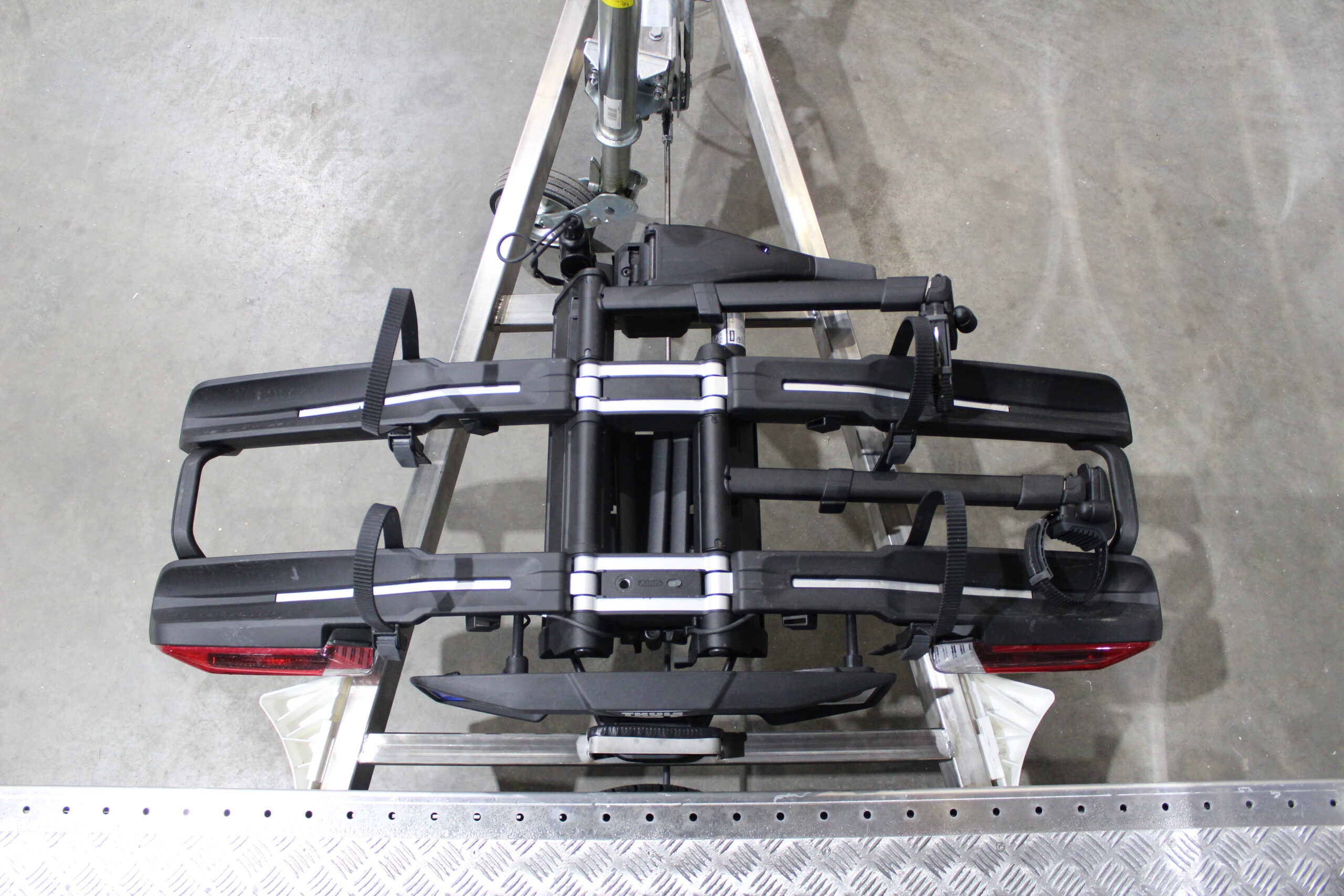 Aluminium Plattformanhänger mit verlängerter Zugdeichsel und Fahrradträger auf der Deichsel in einer Halle vor einem Tor