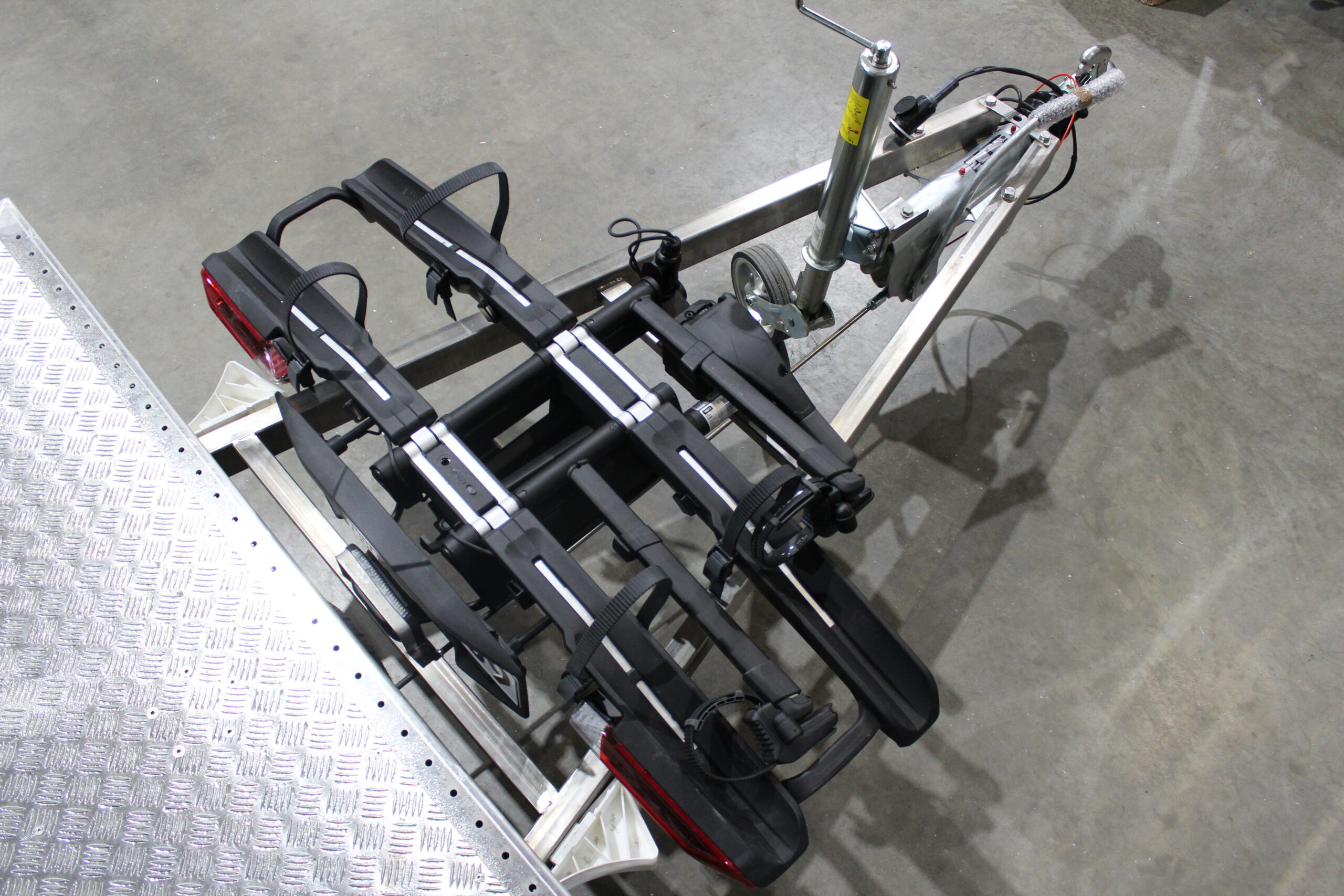 Aluminium Plattformanhänger mit verlängerter Zugdeichsel und Fahrradträger auf der Deichsel in einer Halle vor einem Tor