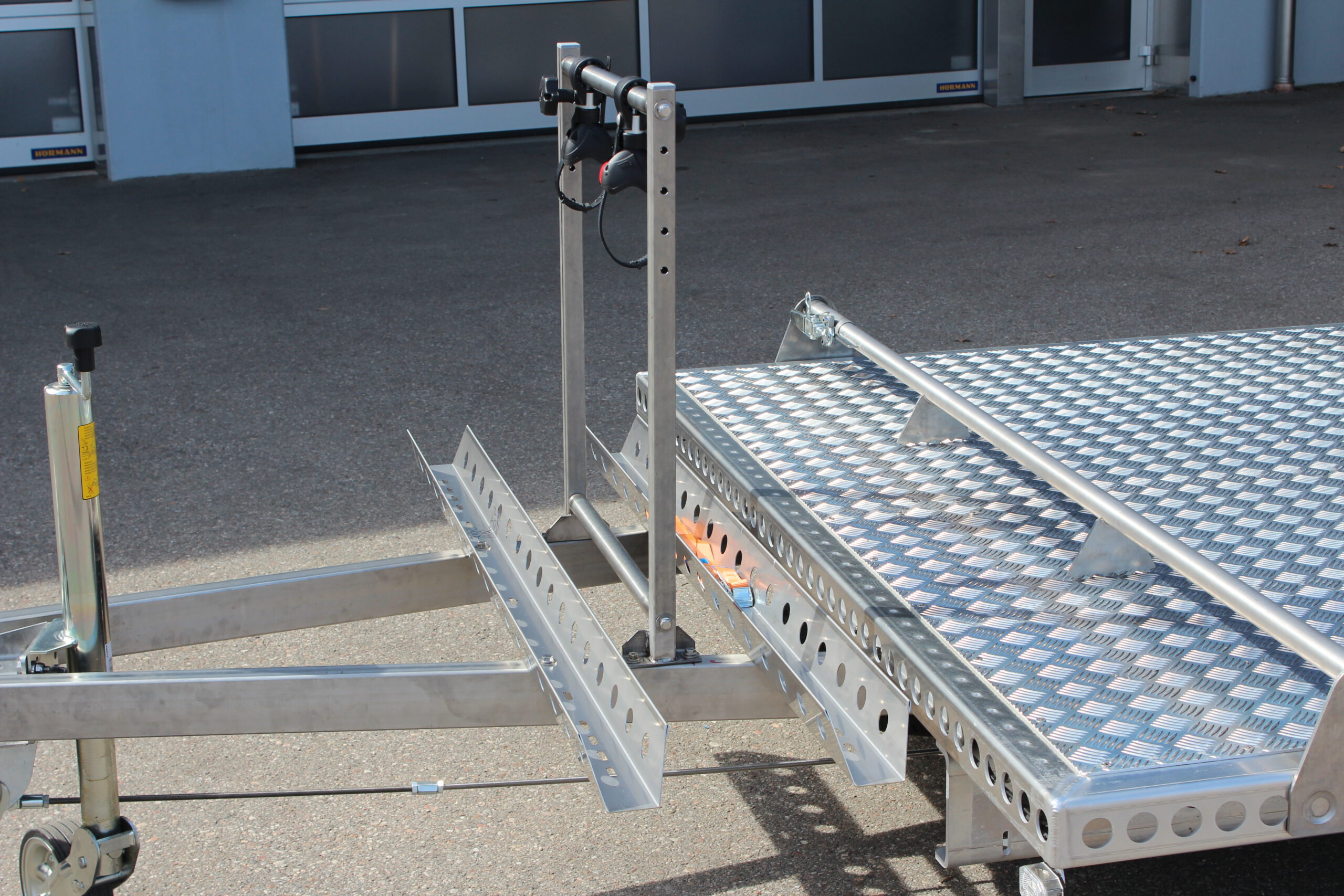 Fahrradträger für 2 Fahrräder aus Edelstahl an einem Anhänger befestigt vor einer Halle