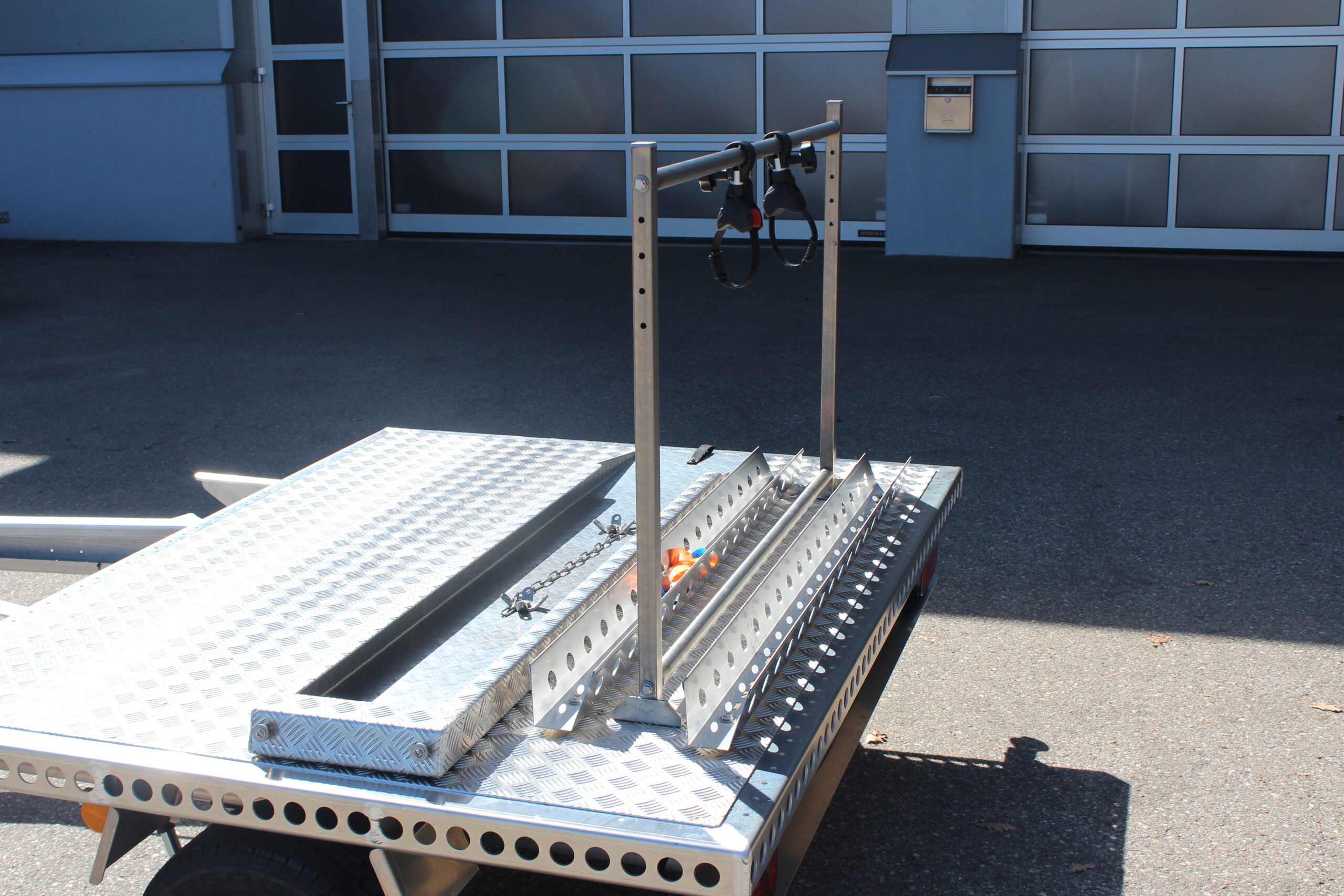 Fahrradträger für 2 Fahrräder aus Edelstahl auf der Plattform eines Anhängers befestigt vor einer Halle