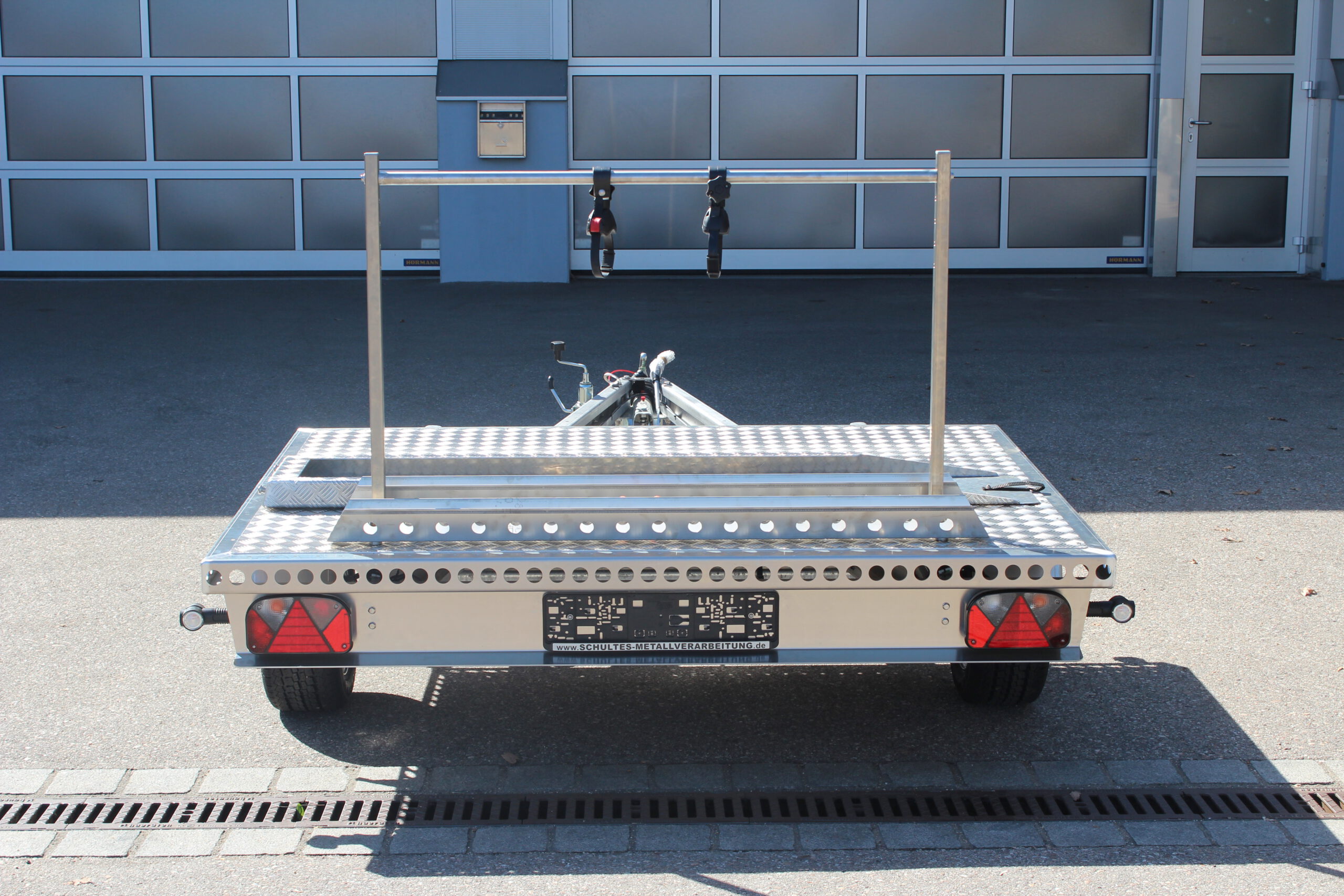 Fahrradträger für 2 Fahrräder aus Edelstahl auf der Plattform eines Anhängers befestigt vor einer Halle