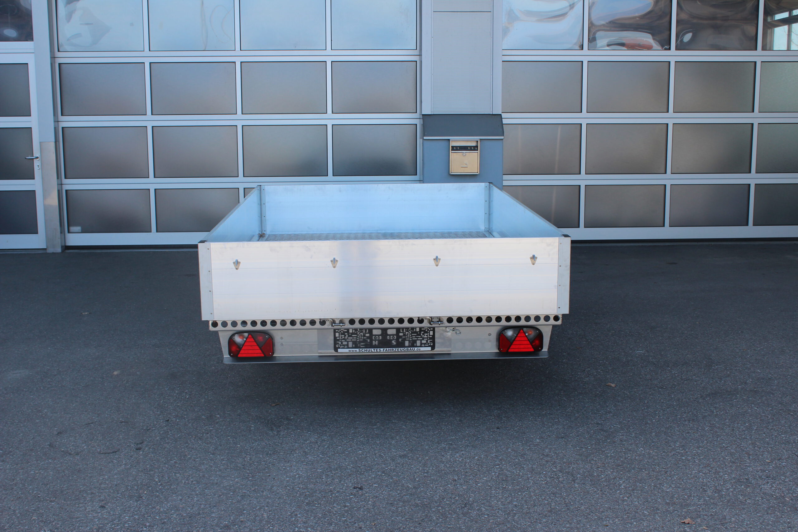Aluminium Anhänger mit Alu Bordwänden umlaufend 40cm hoch vor einer Halle