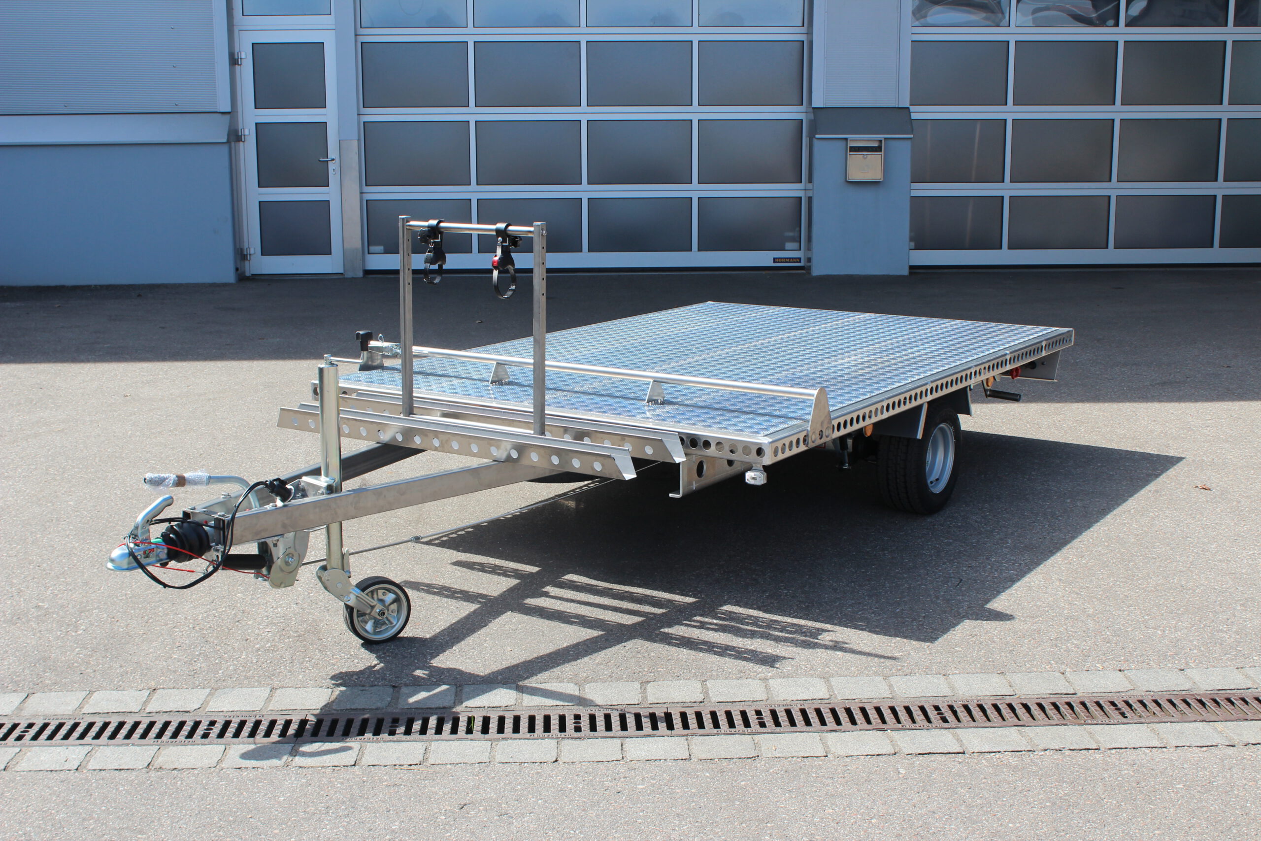 Aluminium Anhänger mit einem Edelstahl Fahrradträger auf der Zugdeichsel vor einer Halle