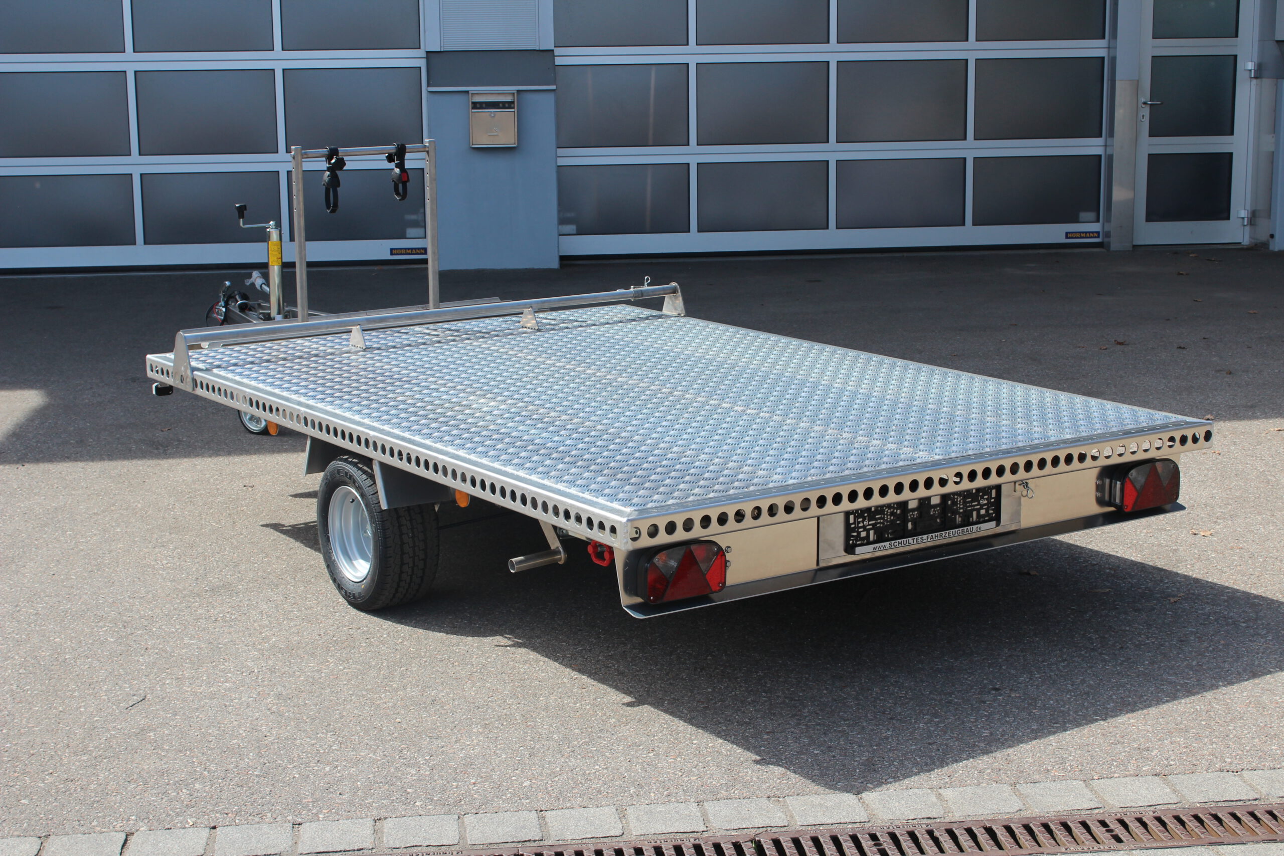 Aluminium Anhänger mit einem Edelstahl Fahrradträger auf der Zugdeichsel vor einer Halle