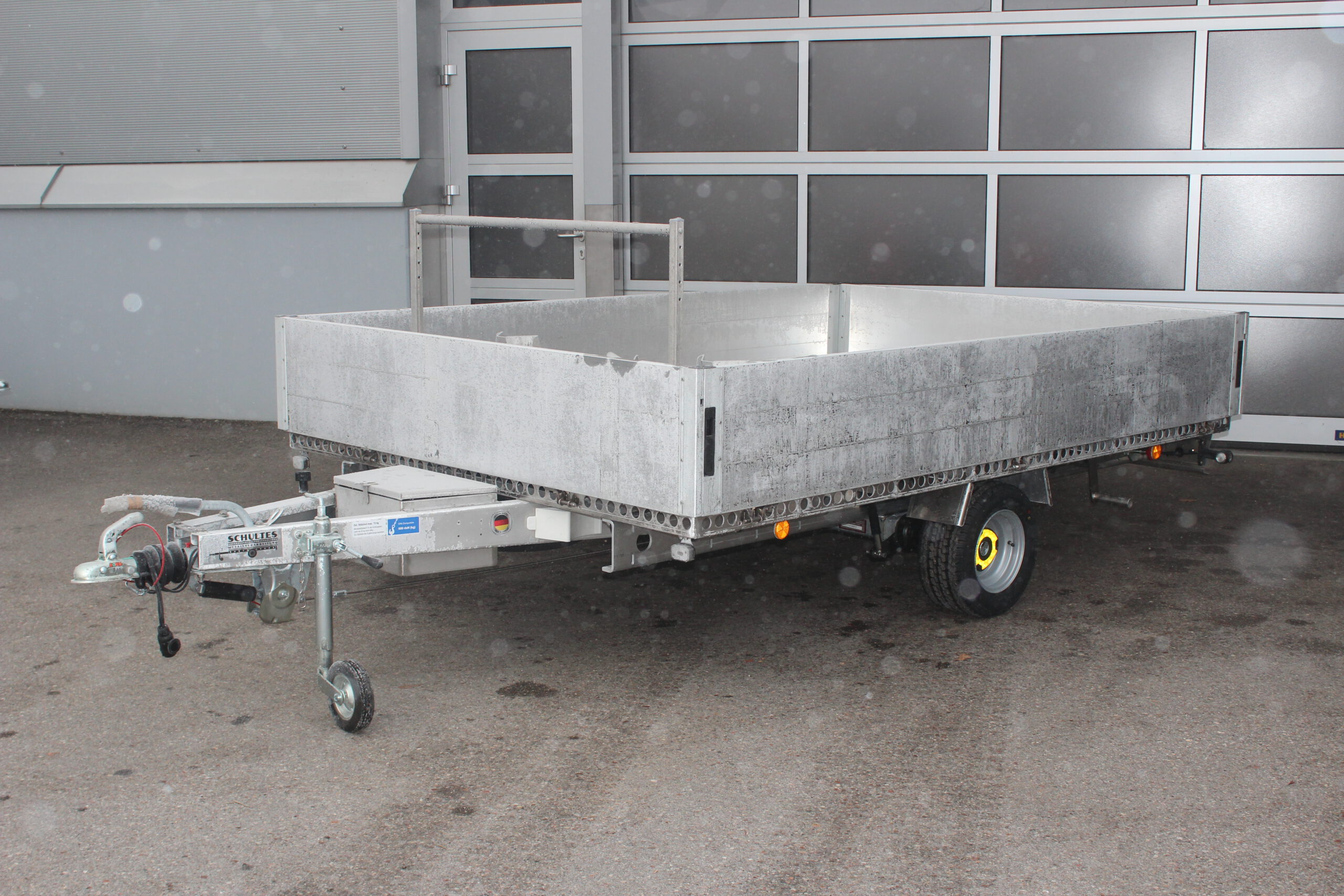 Aluminium Anhänger mit Bordwänden und Fahrradträger vor einer Halle