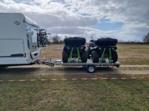 Aluminium Anhänger mit zwei Quad beladen an einem Wohnmobil auf einer Wiese
