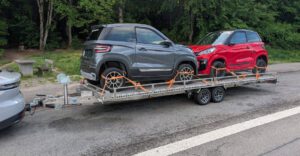 Aluminium und Edelstahl Plattformanhänger, 6Meter lang, mit zwei Mopedautos beladen auf einem Parkplatz