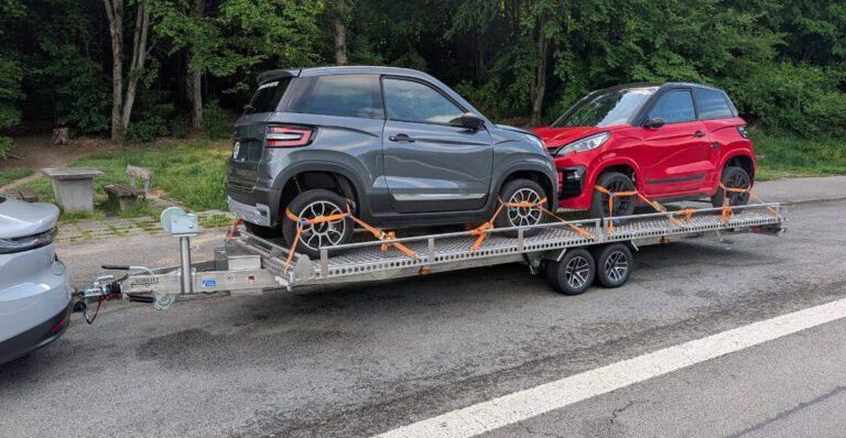 Aluminium und Edelstahl Plattformanhänger, 6Meter lang, mit zwei Mopedautos beladen auf einem Parkplatz