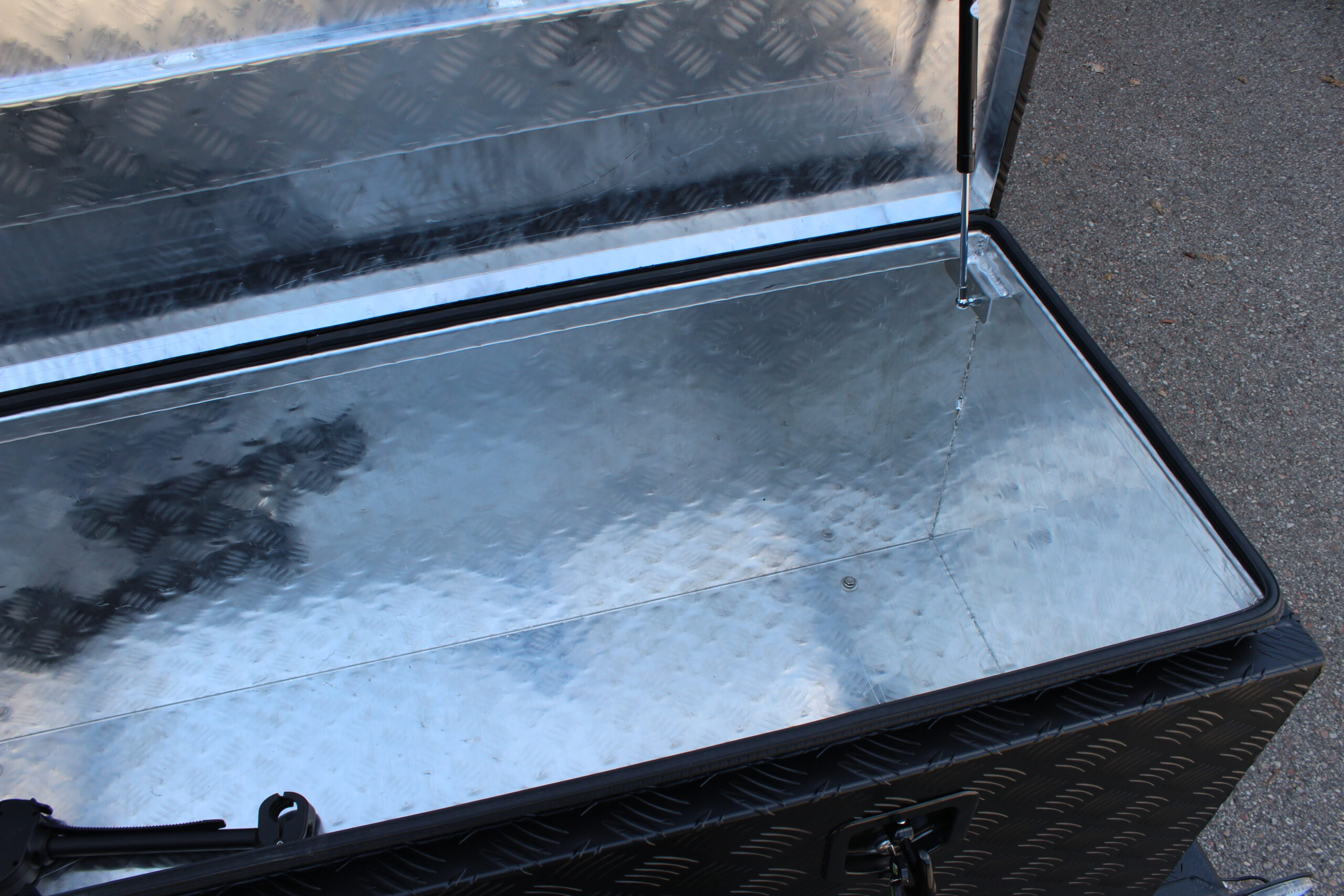 Große Aluminium Transportbox vorne quer auf einem Anhänger montiert, schwarz lackiert